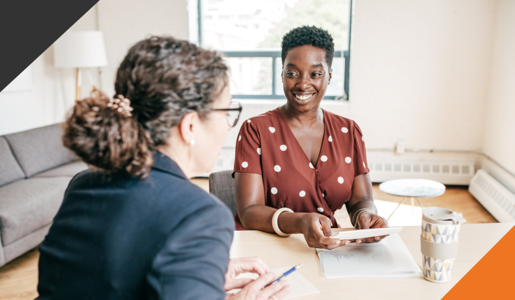 two women seated ata desk in an office discussing empathetic leadership