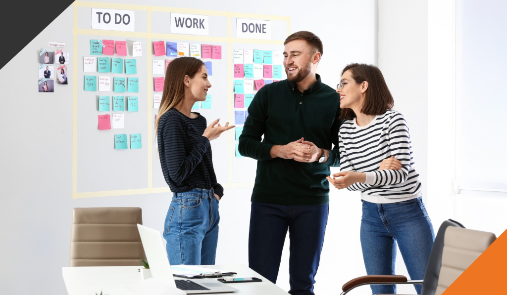 three employees in a meeting room working through task lists demonstrating 4 ways to improve productivity at work