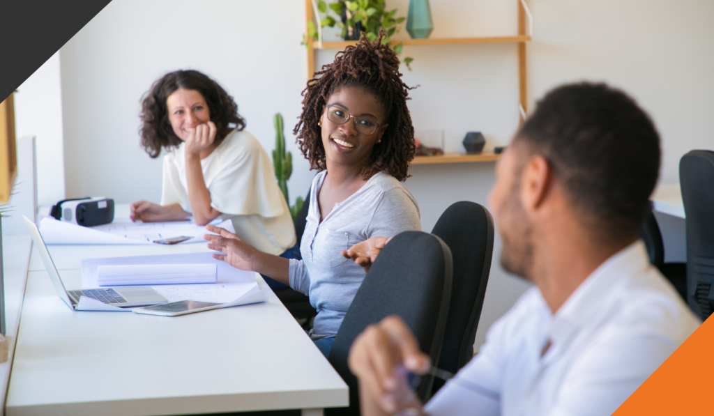 three employees seated in a row at a desk in an office 