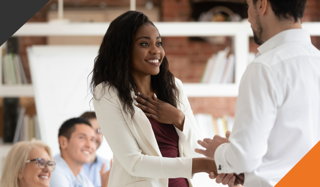 one employee is rewarded for growth mindset with a handshake from another employee